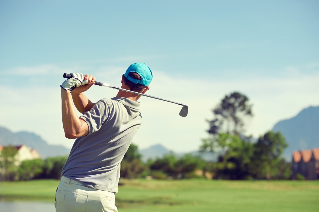 a picture of a person golfing with a green scenic background